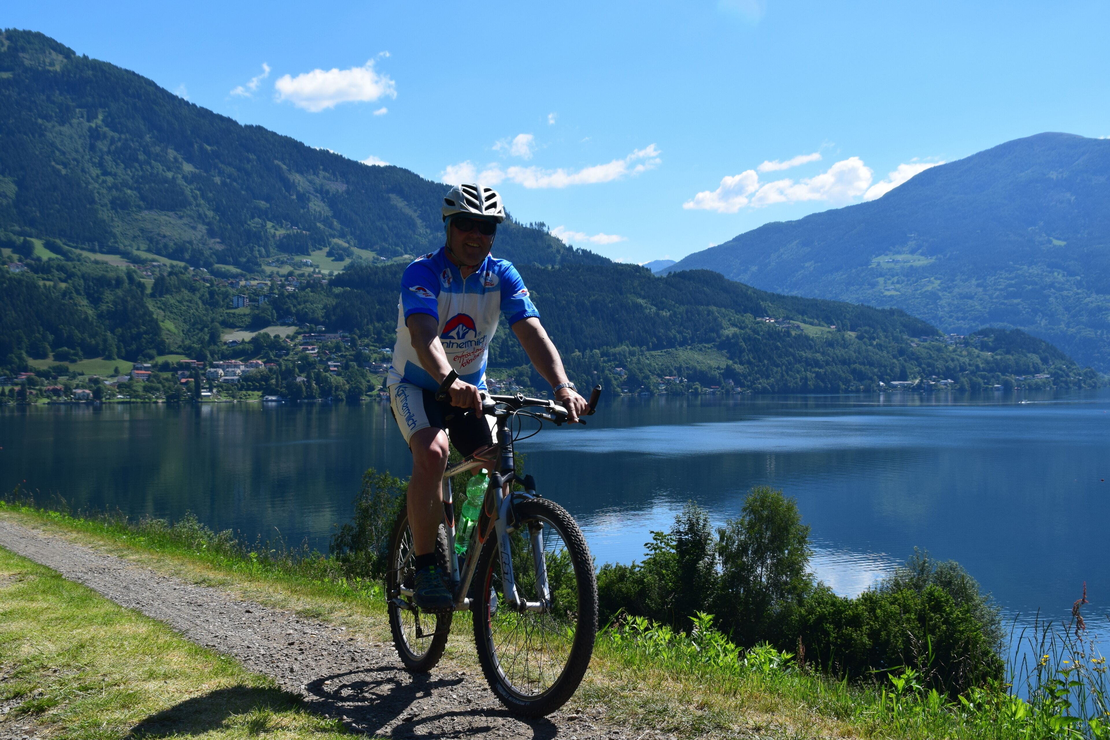 En cyklist på en mountainbikeled med en sjö och berg i bakgrunden.