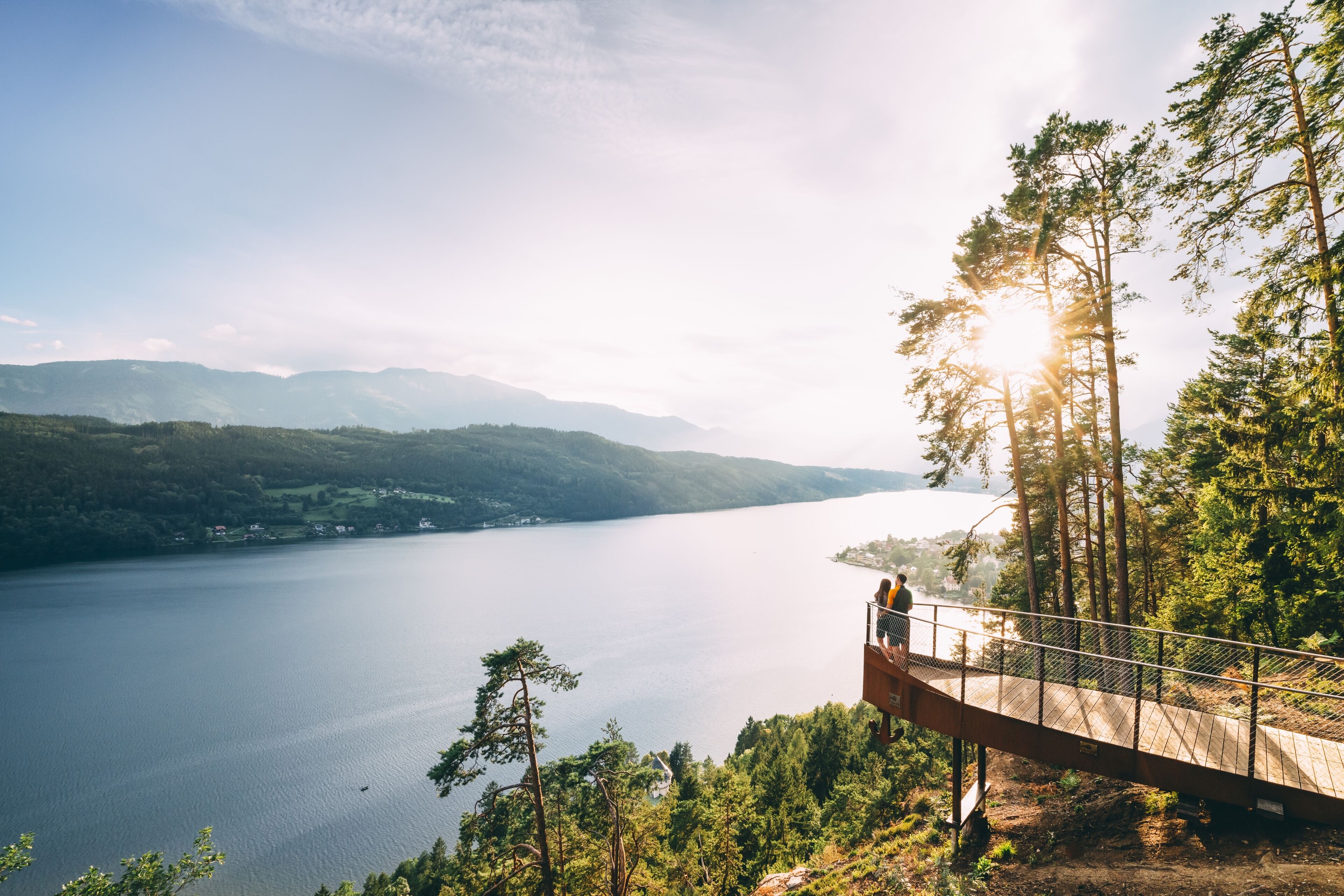 A wooden viewing platform overlooking a lake with mountains in the background.
