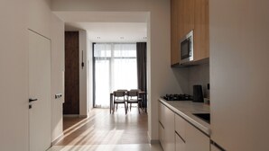 A modern kitchen with wooden cabinets, a microwave, and a dining area with chairs. - RIS Central Apartments Yerevan (Yerevan)