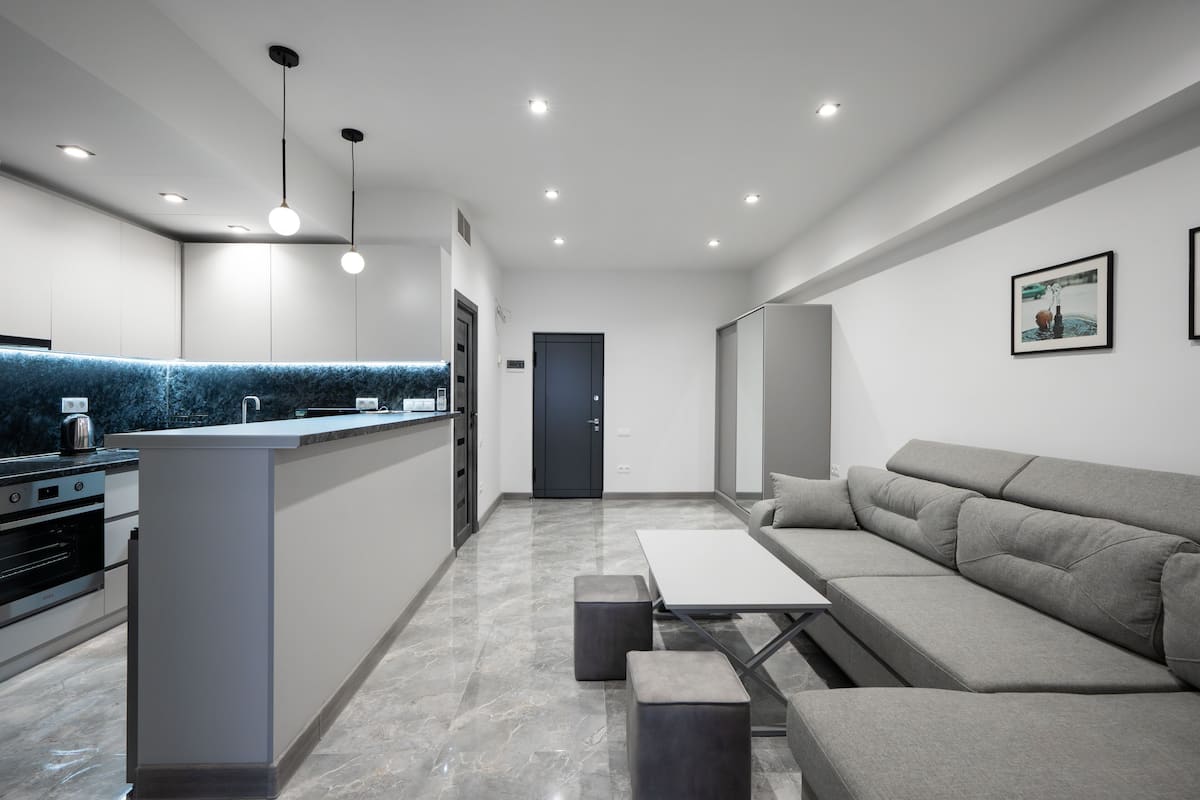 A modern kitchen with a central island, a built-in oven, and a dark-colored door.