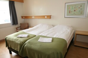 A hotel room with two beds, a wooden nightstand, a chair, and a framed picture on the wall. - Akranes Guesthouse (Akranes)