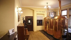 A hotel room with a wooden desk, a large copper distillation apparatus, and a sign reading "Dej báh stési". - Hotelové pokoje Kolčavka (Prague)