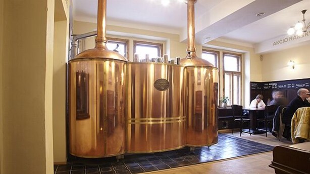 A room with a large copper distillation apparatus, a piano, and a dining area with a table and chairs. - Hotelové pokoje Kolčavka (Prague)