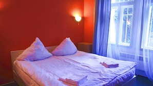 A bed with white linens and pillows, a bedside table, and a window with curtains. - Hotelové pokoje Kolčavka (Prague)