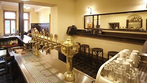 A bar area with a tap system, stools, and a counter with bottles. - Hotelové pokoje Kolčavka (Prague)