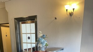A reception desk with a vase of flowers, a sign reading "GUESTS," and a wall-mounted light fixture. - Ivydene Guest House (Skegness)