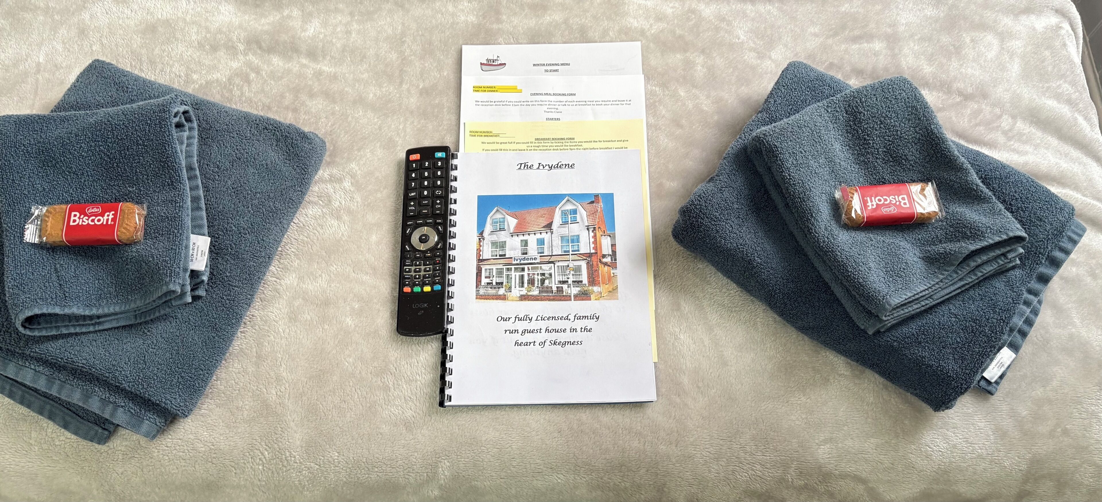 A remote control, a booklet, and two Biscuits chocolate bars on a textured surface.