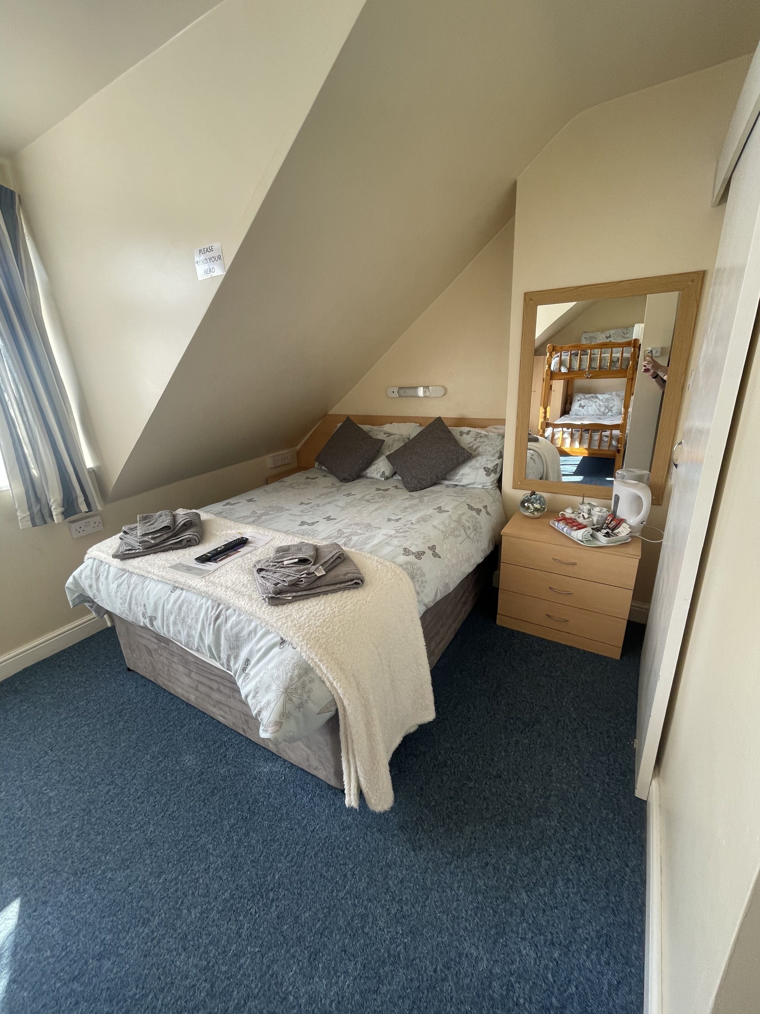 Ein Schlafzimmer mit Etagenbett, Nachttisch mit Spiegel, Lampe und kleinem Schrank.
