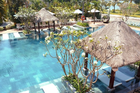 Una piscina al aire libre, sombrillas, sillones reclinables de piscina