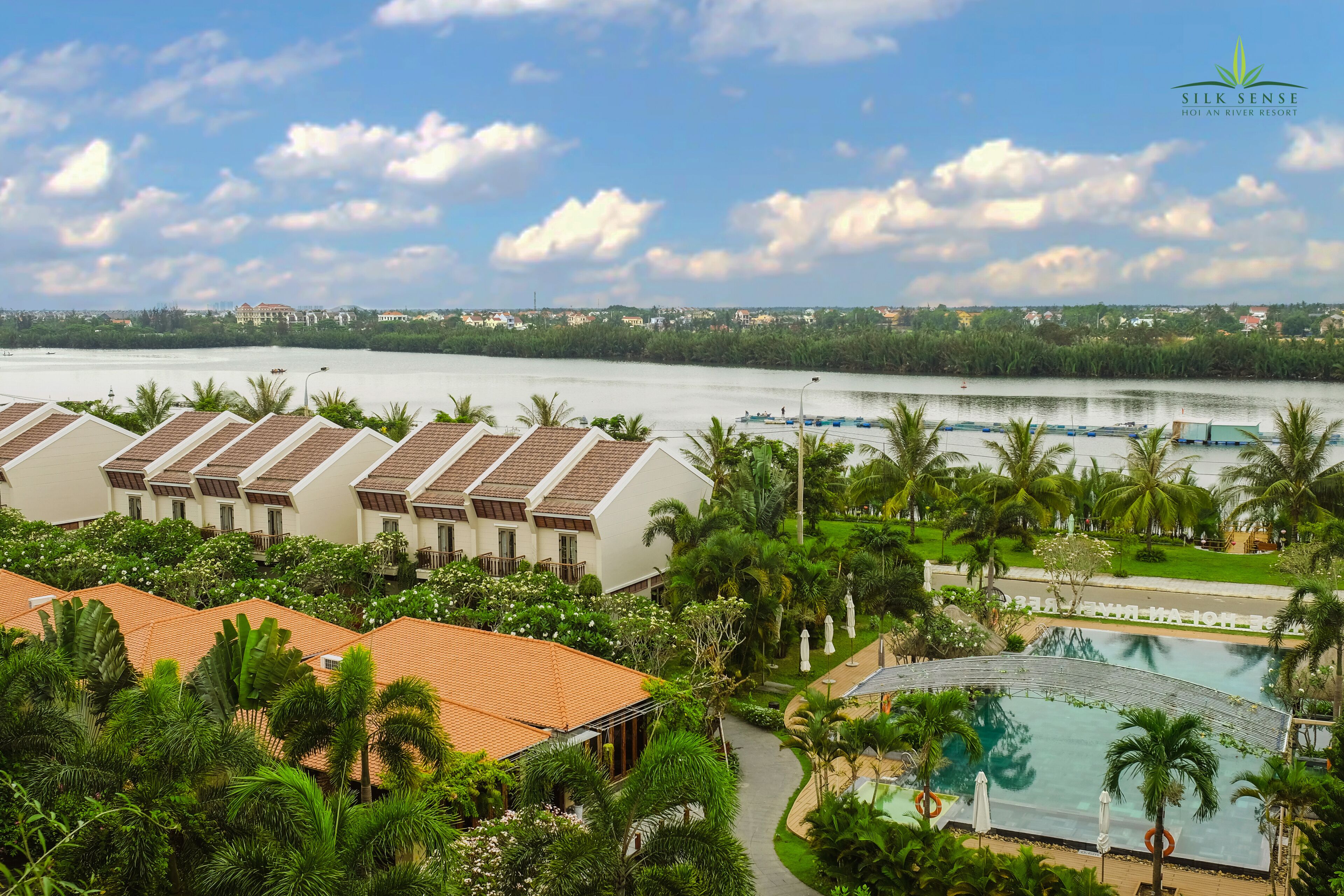 Un complexe hôtelier comprenant plusieurs bâtiments de style bungalow, une piscine et offrant une vue sur la rivière.