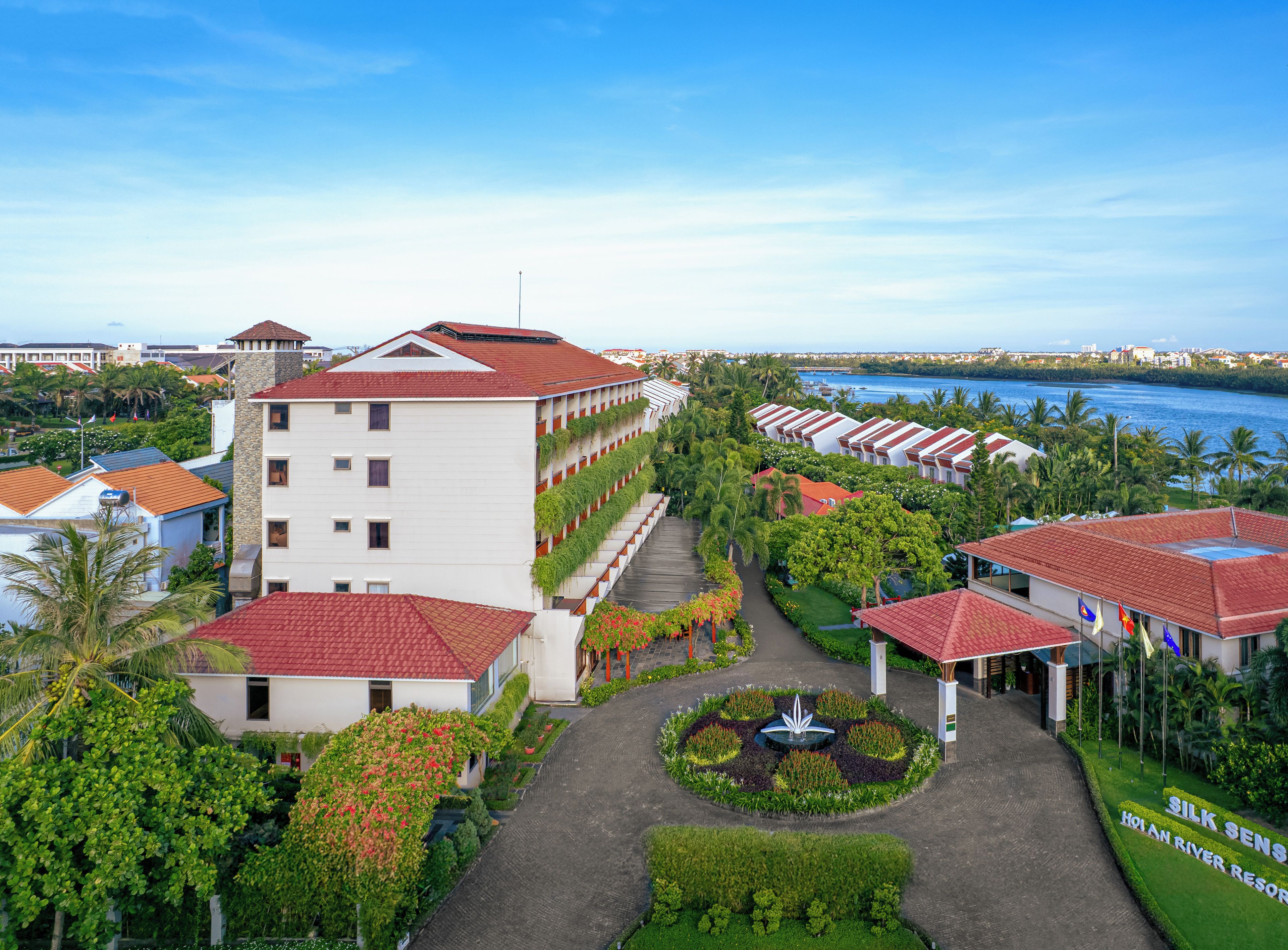 Un resort con varias construcciones, un patio central y vistas al río.
