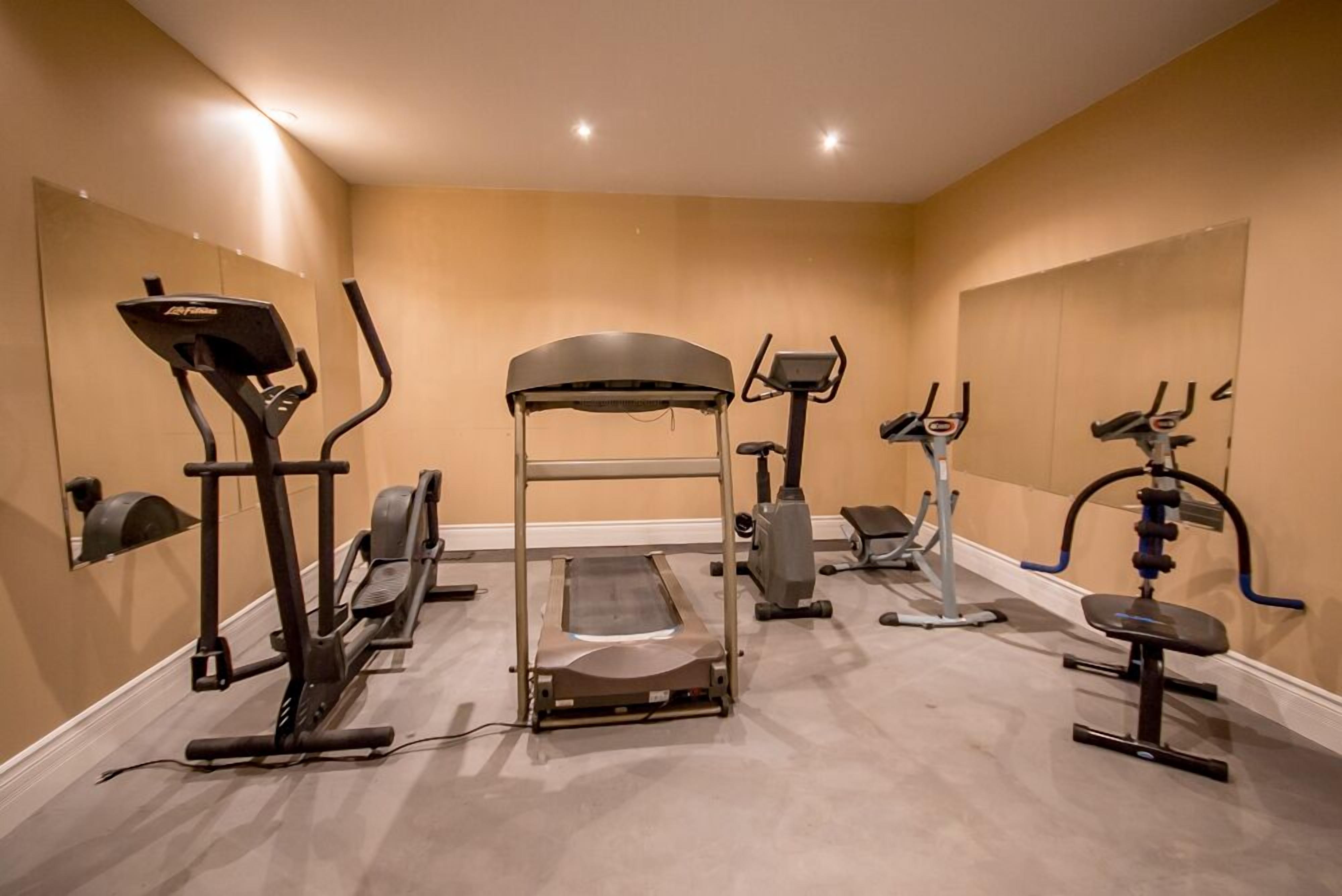 A home gym with a treadmill, elliptical, and weight machine.