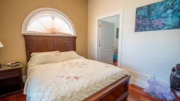 A bedroom with a wooden bed, a nightstand, a window with a white frame, and a painting on the wall.