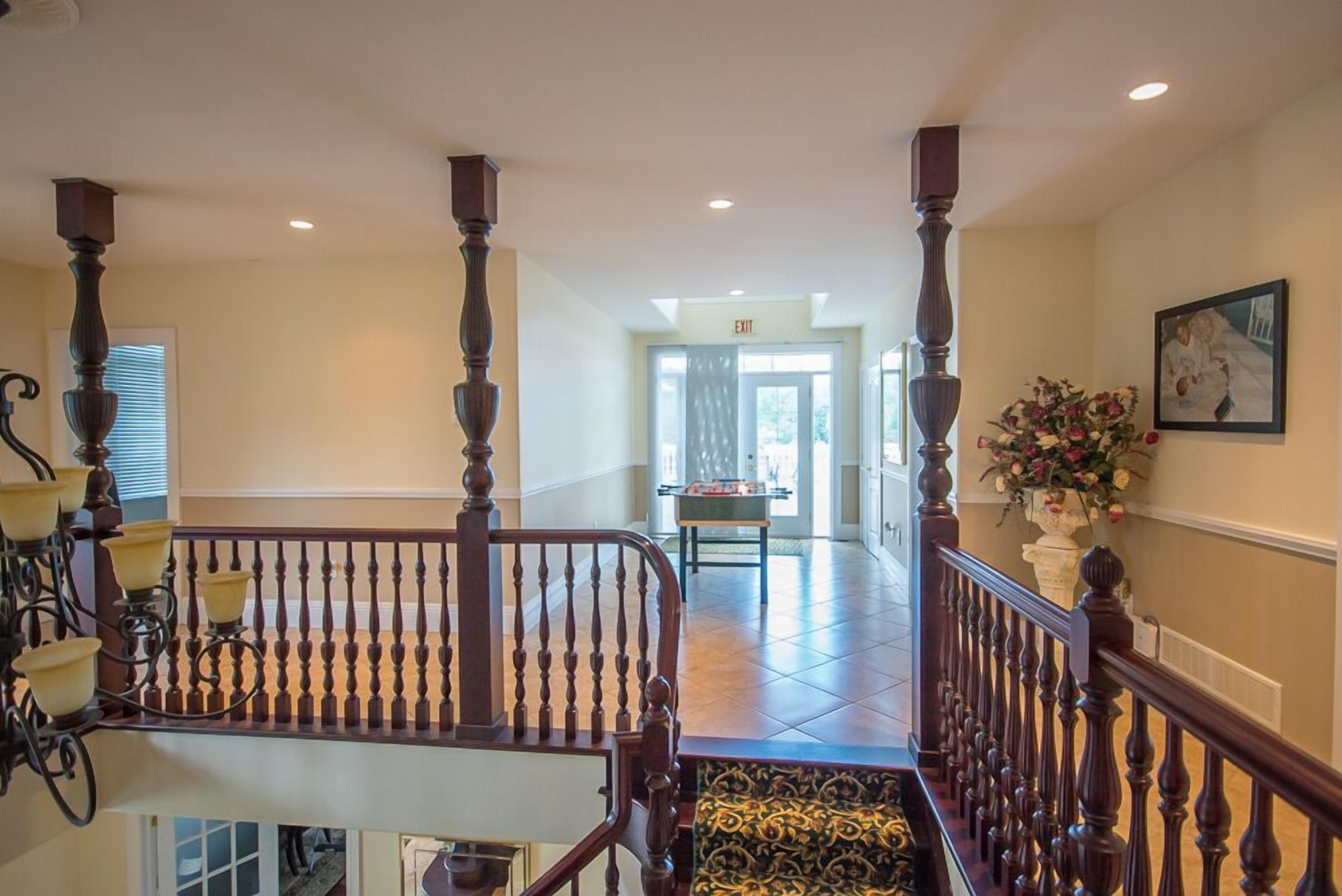 Eine prachtvolle Treppe mit aufwendiger Balustrade, einem Chandelier und Blick zum Eingang.