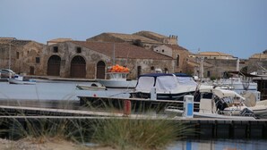Marina con barcos amarrados, un edificio con ventanas arqueadas y cielo despejado.