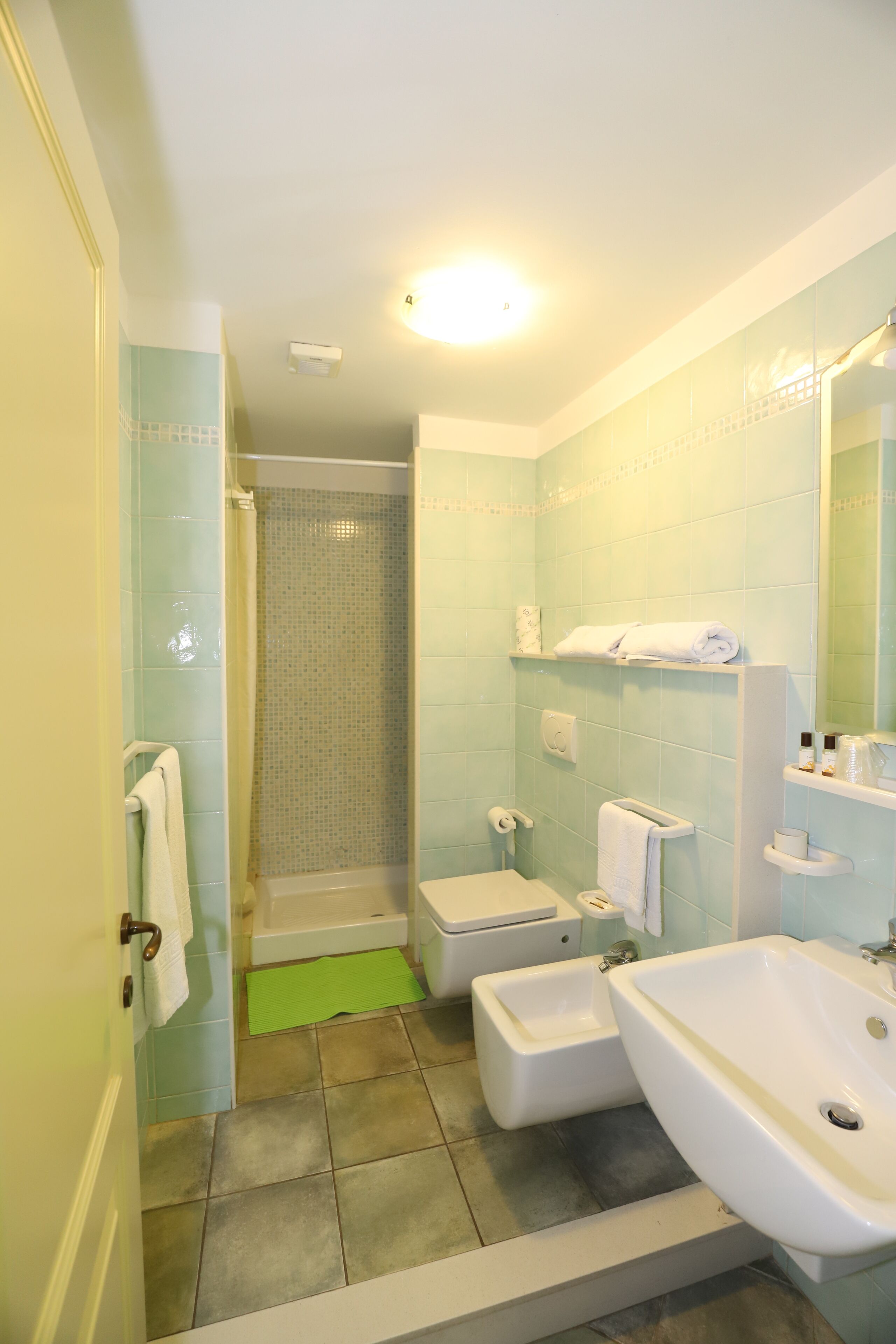 Ein Badezimmer mit Dusche, zwei Waschbecken, Toilette und Spiegel.
