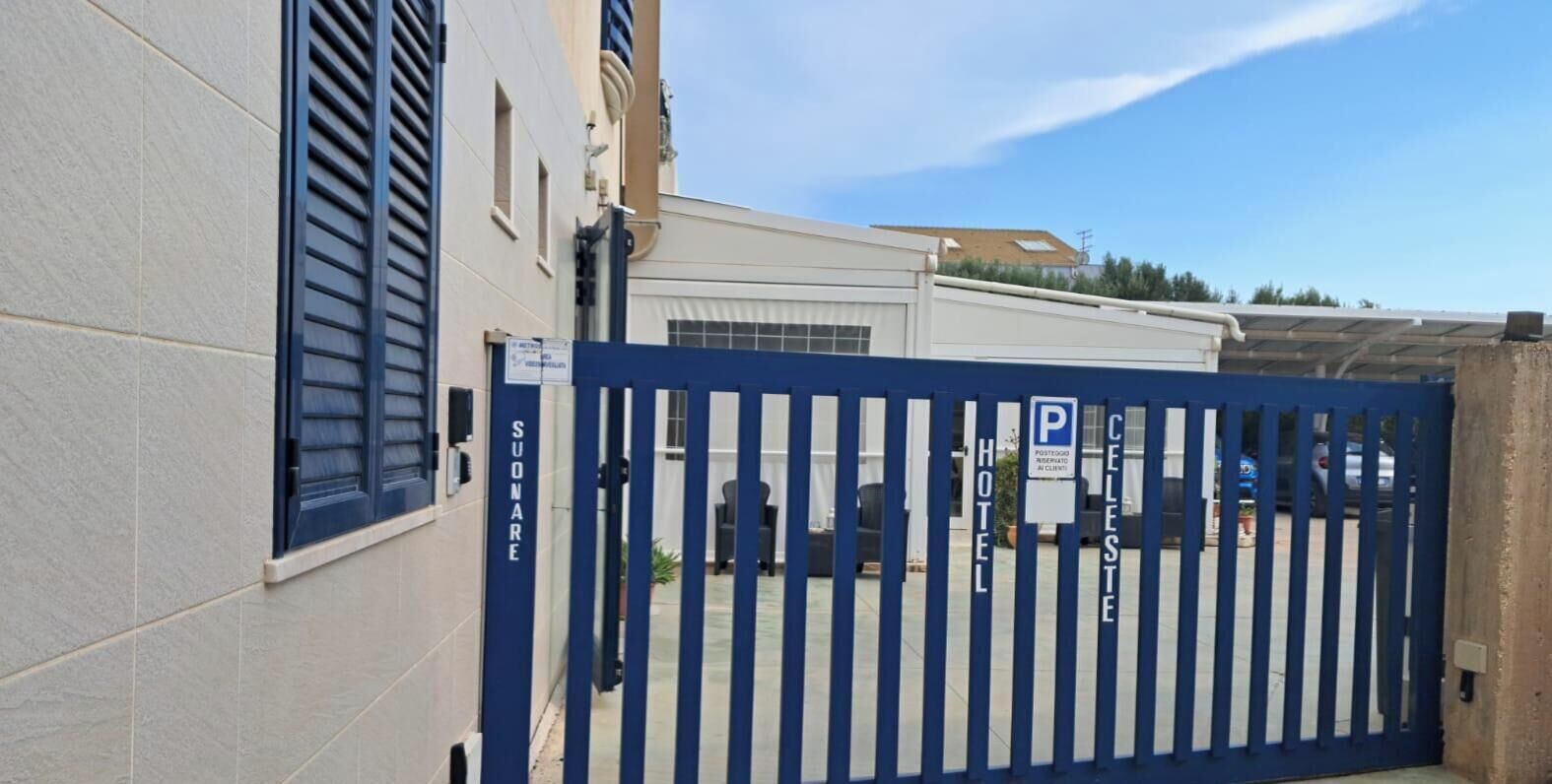 Una entrada con reja a un hotel, con un cartel que indica un estacionamiento.