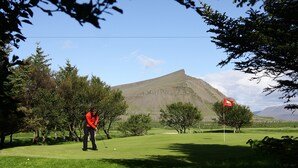 A golf course with a mountain in the background, trees, and a clear sky. - Gallery Guesthouse StayWest (Akranes)