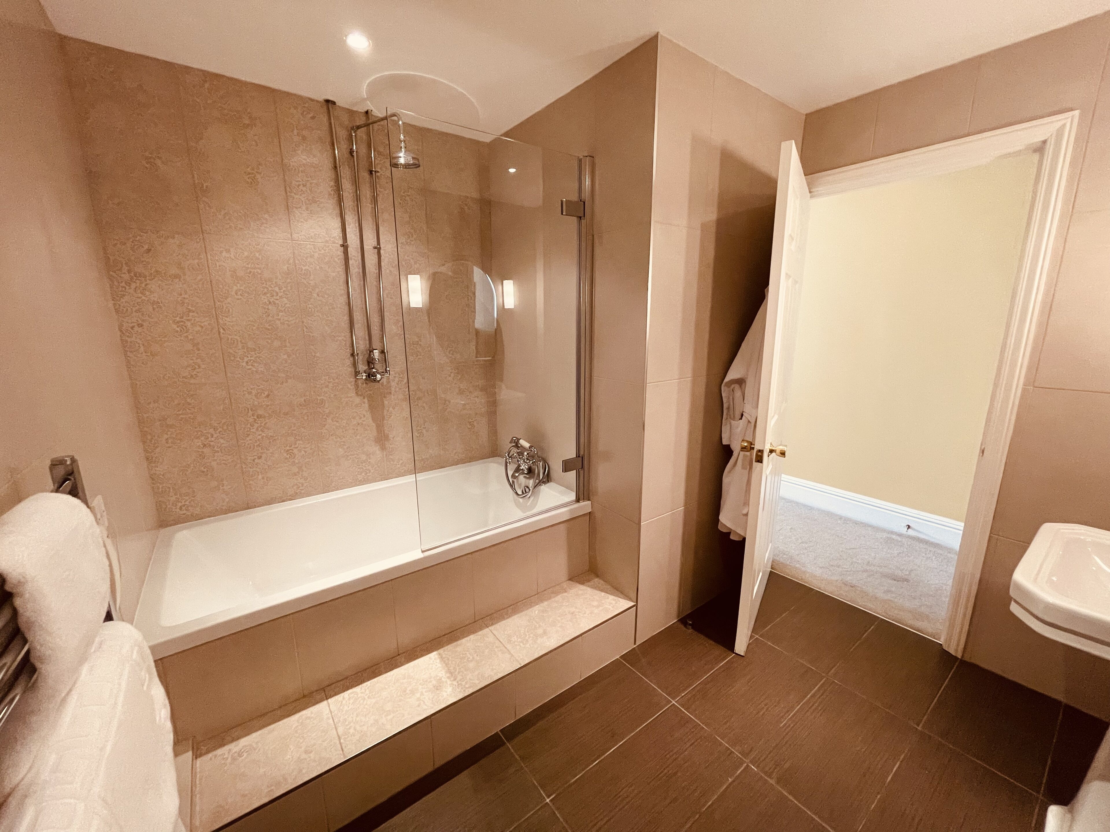 A modern bathroom with a glass-enclosed shower, a freestanding bathtub, and a separate sink area.