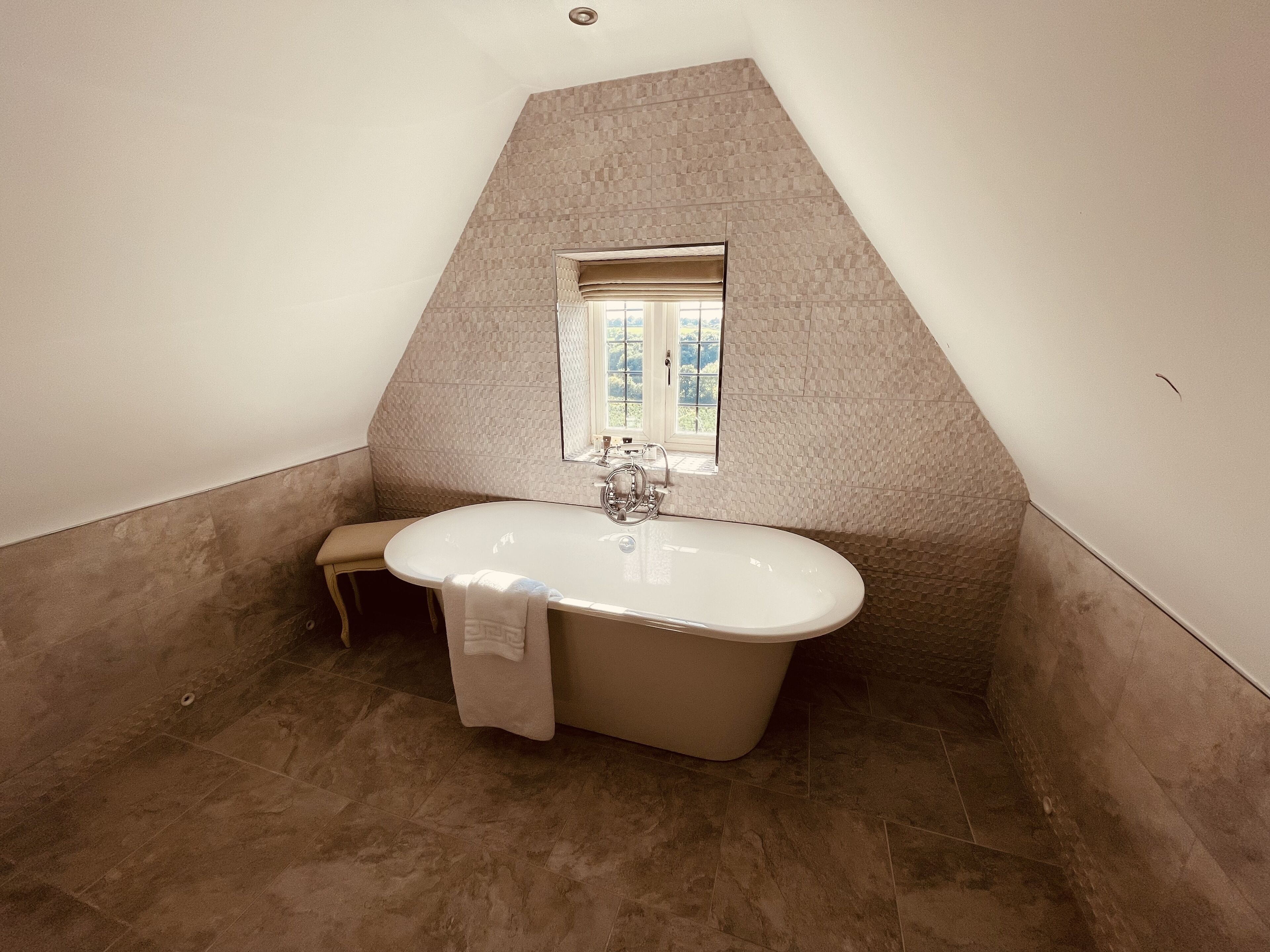 A bathroom with a freestanding bathtub, a window, and a towel hanging on the wall.