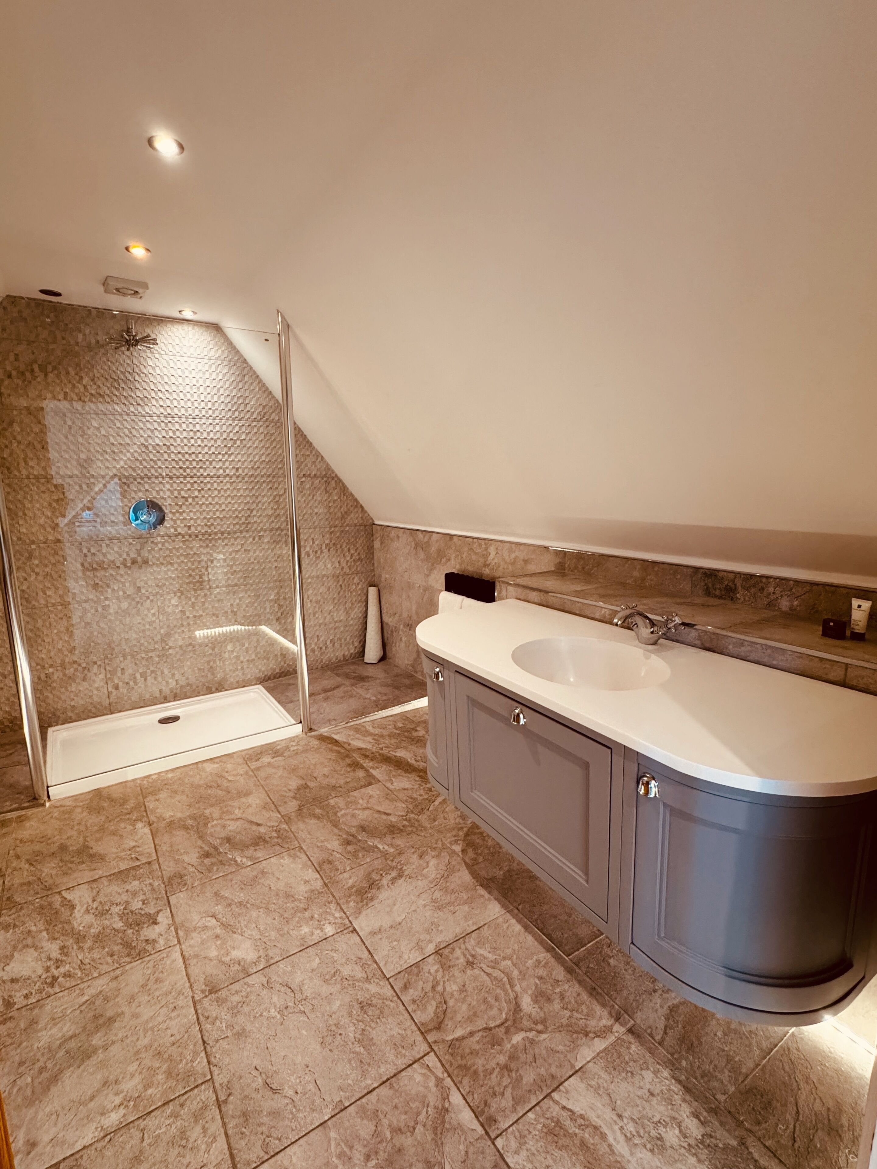 A modern bathroom with a walk-in shower, a double sink vanity, and a large mirror.