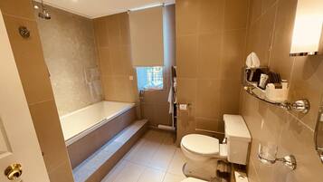 A modern bathroom with a bathtub, toilet, and shower.