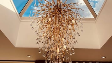 A modern chandelier with a complex design hanging from a ceiling with a skylight.