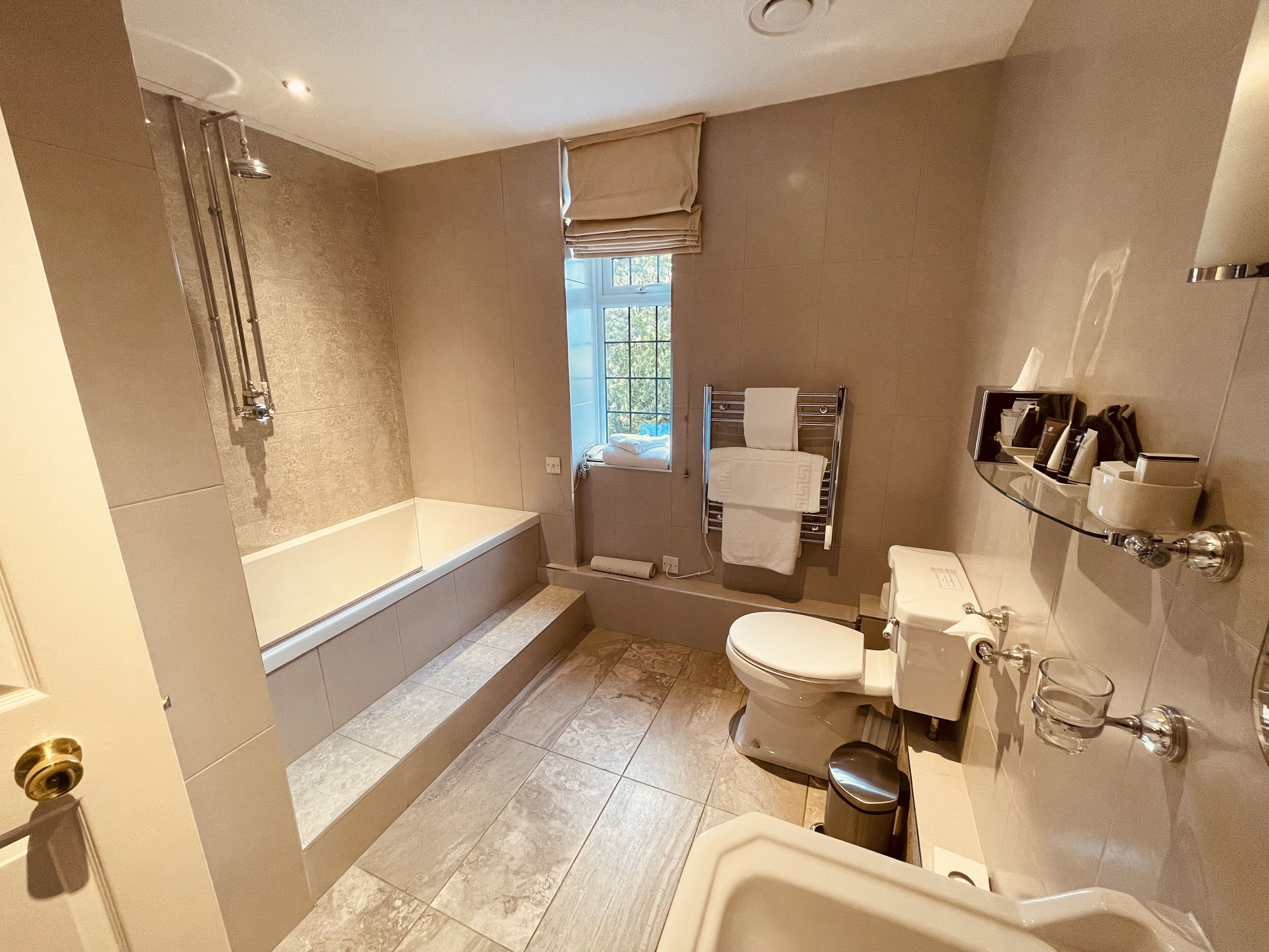 A modern bathroom with a bathtub, toilet, and shower.