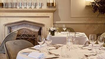 A dining room with a fireplace, a mounted deer head, and a row of wine glasses above it.