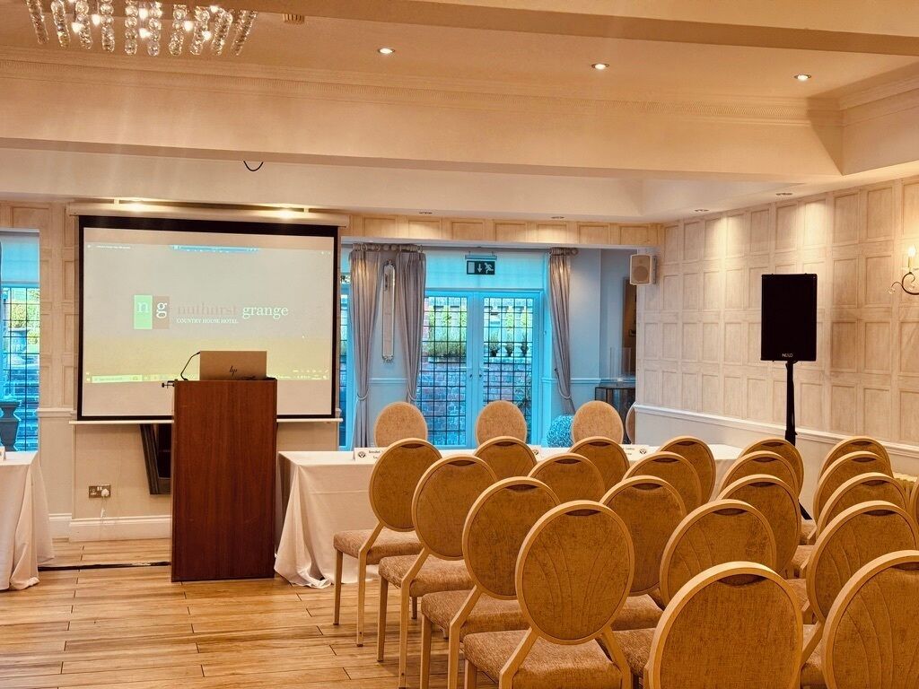 A conference room with a podium, a screen, and rows of chairs.