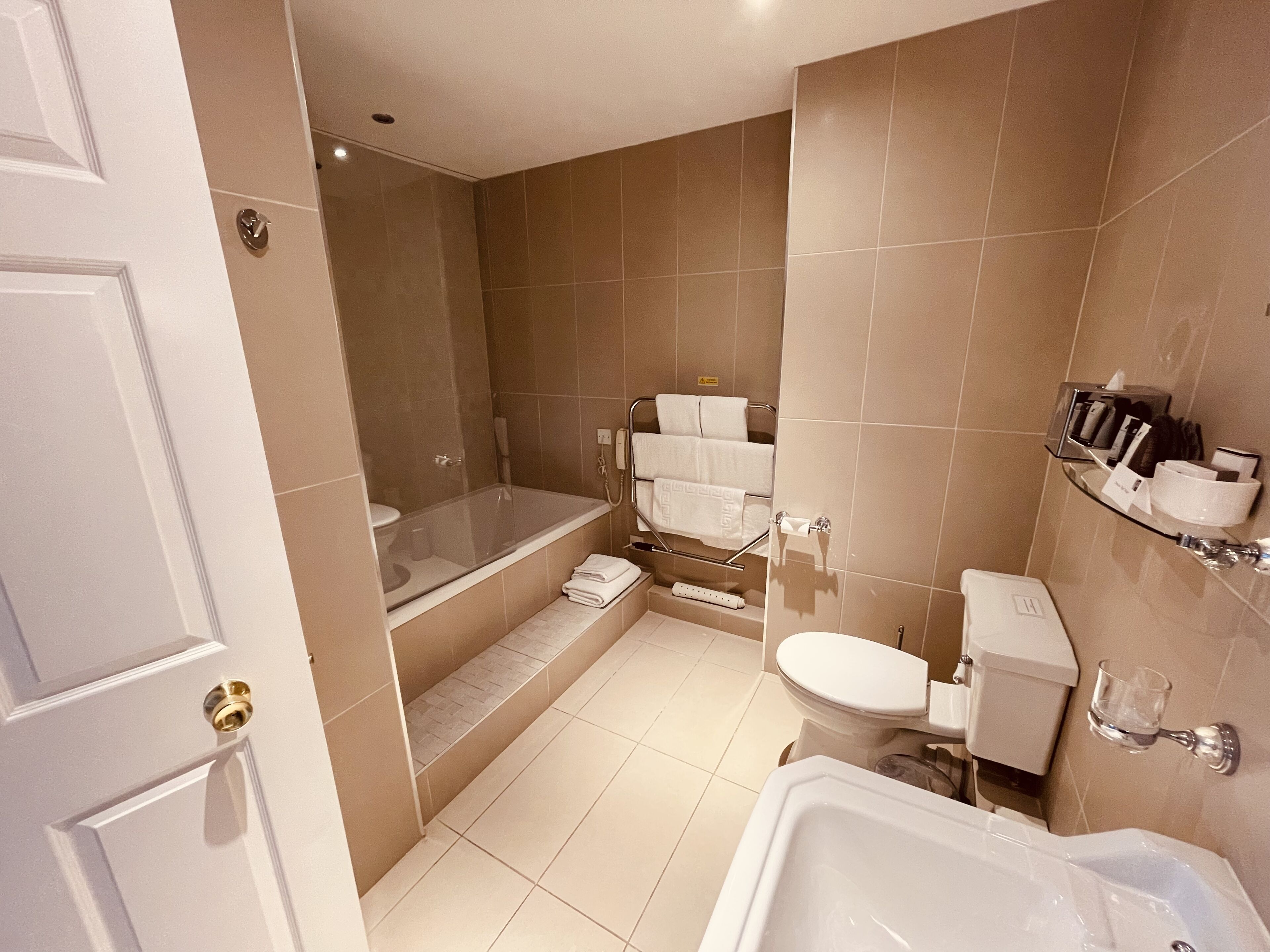 A modern bathroom with a bathtub, toilet, and shower.