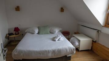 Een slaapkamer met een bed, nachtkastje, lamp, radiator en raam.