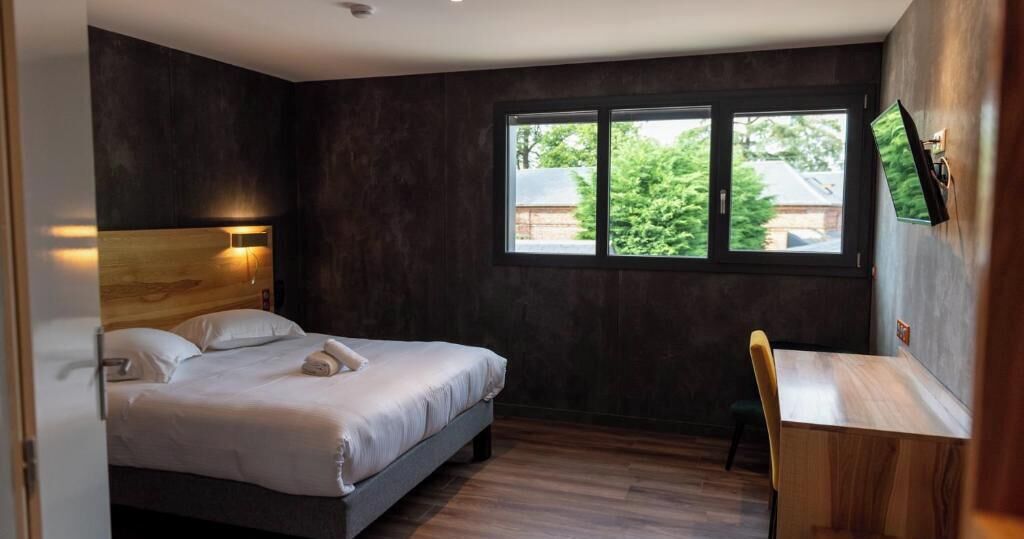 Ein Schlafzimmer mit einem Bett, einem Schreibtisch und einem Fenster.