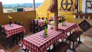 An outdoor dining area with checkered tablecloths, wooden chairs, and a view of the countryside. - Hotel Casa Cantabria (Villa de Leyva)