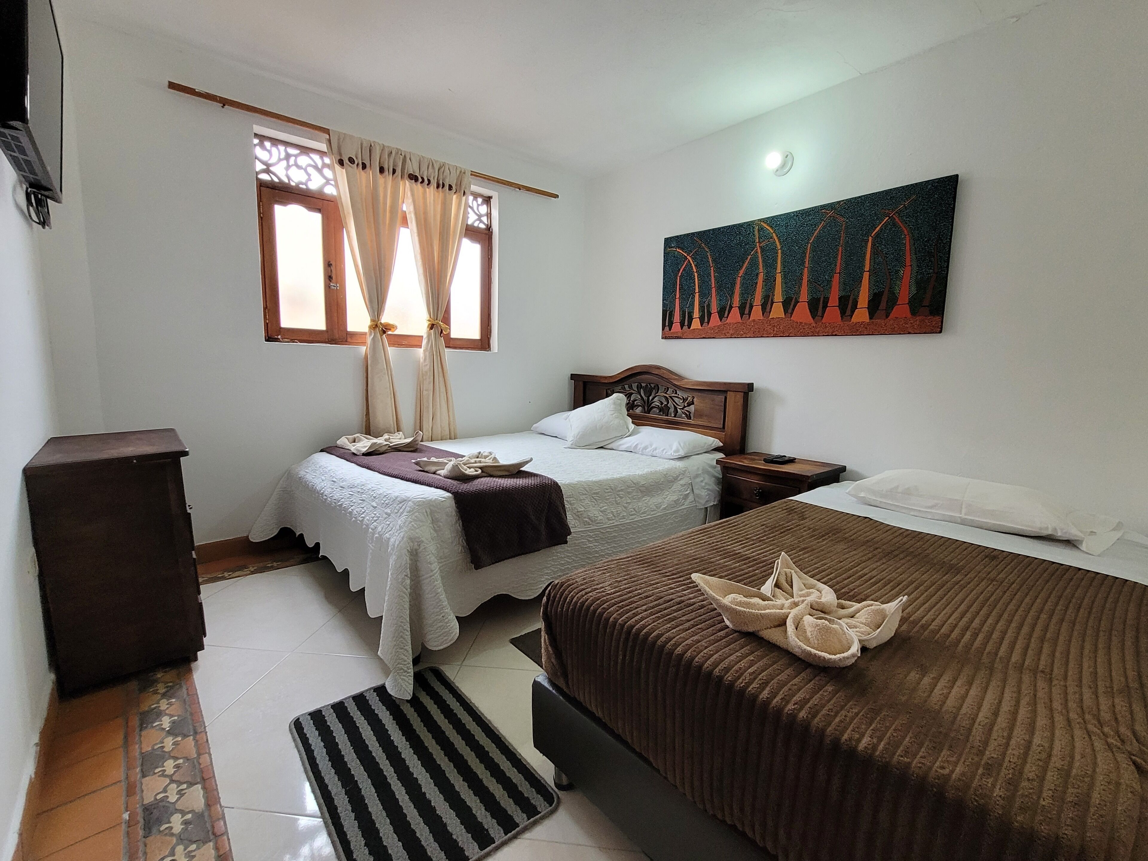 A bedroom with two beds, a nightstand, a wooden cabinet, a window with curtains, and a painting on the wall.