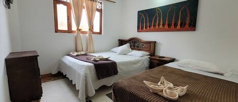 A bedroom with two beds, a nightstand, a wooden cabinet, a window with curtains, and a painting on the wall.
