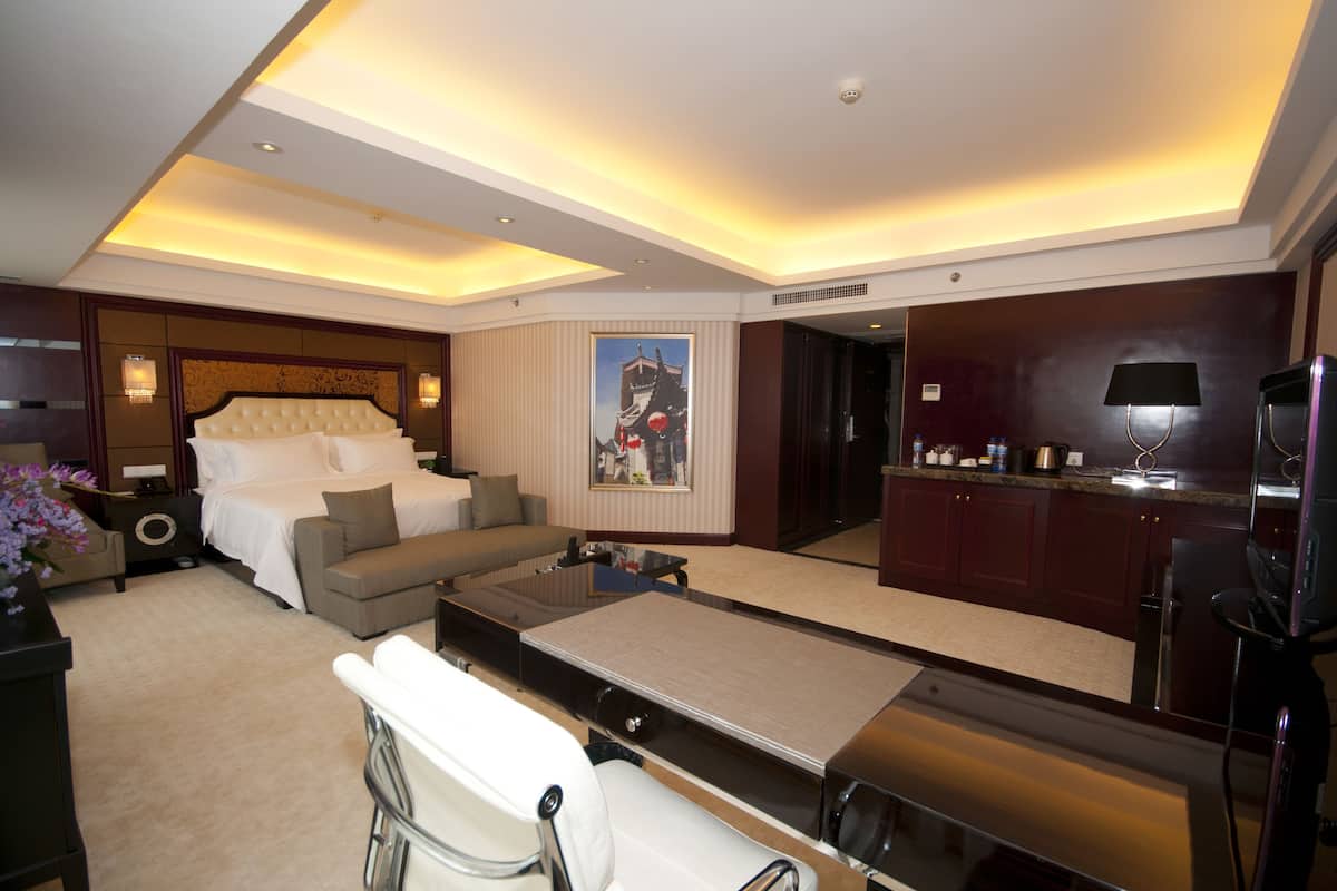 Una habitación de hotel con cama, sofá, mesa de comedor y cocina equipada con refrigerador y microondas.