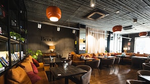 A modern restaurant interior with wooden flooring, leather seating, and pendant lighting. - Málaga Premium Hotel (Málaga)