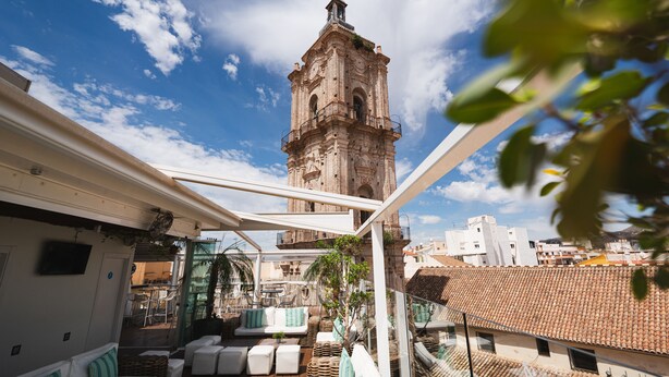A rooftop terrace with outdoor seating, a view of a historic tower, and a clear blue sky. - Málaga Premium Hotel (Málaga)