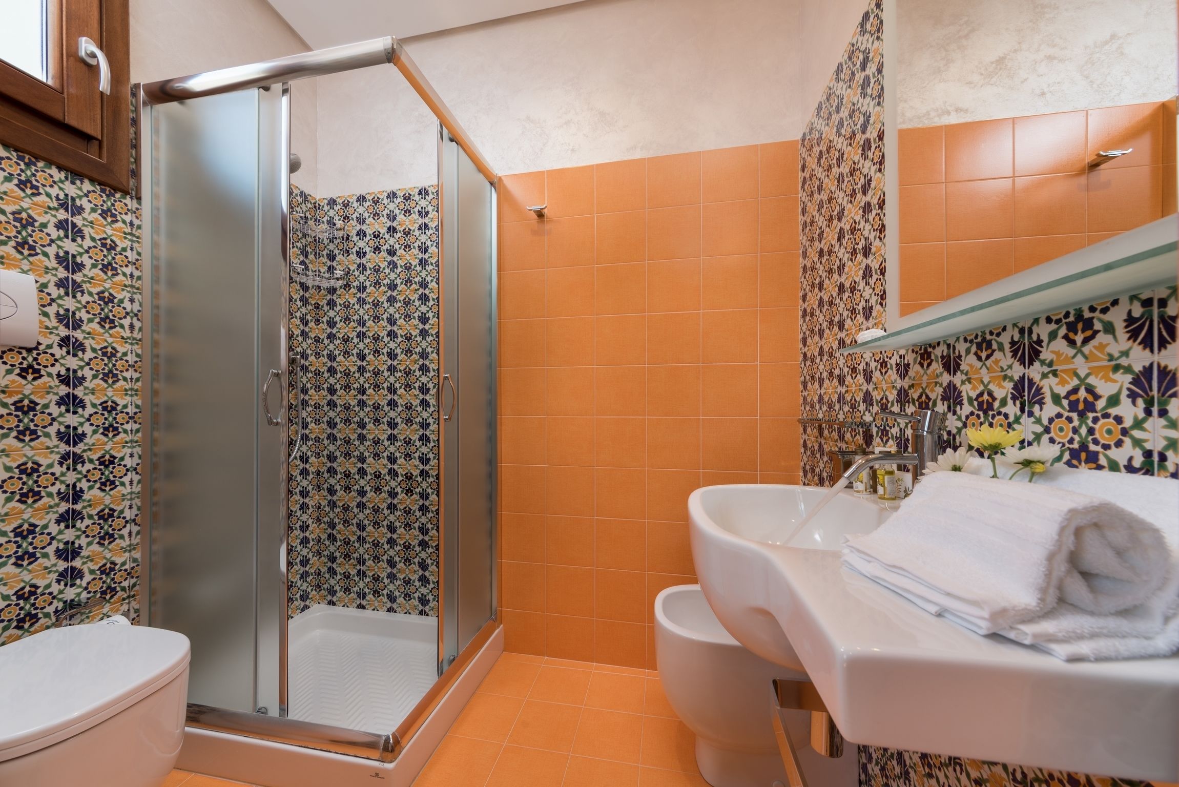 Un baño con ducha de mampara de vidrio, un lavabo blanco y un inodoro.
