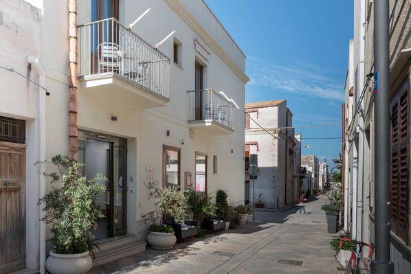 Una calle estrecha con edificios que tienen balcones y plantas en macetas.
