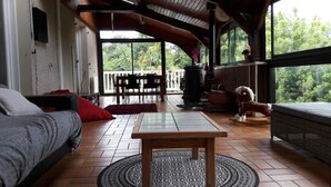 Een gezellige woonkamer met een bank, een salontafel en een schommelpaard. Er is een balkon met stoelen en uitzicht op groen.