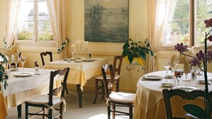 Een eetzaal met twee gedekte tafels, elk met stoelen en servies.