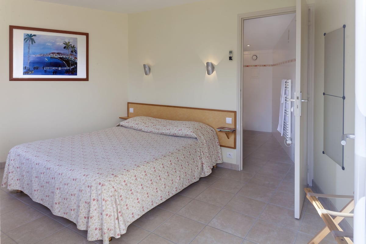 Une chambre à coucher avec un lit, un tableau encadré au mur et deux lampes fixées au mur.