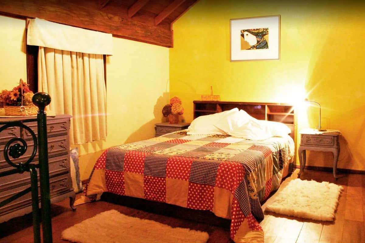 Une chambre confortable avec un lit, une commode, une table de chevet et une lampe.