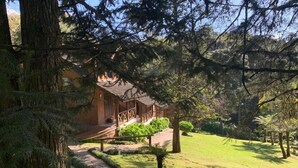 A lodge with a covered porch, a stone pathway, and a well-maintained lawn. - Chalets do Vale (Gramado)