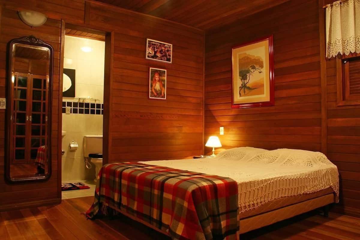 Une pièce en bois avec un lit, un miroir, un tableau encadré et une lampe.