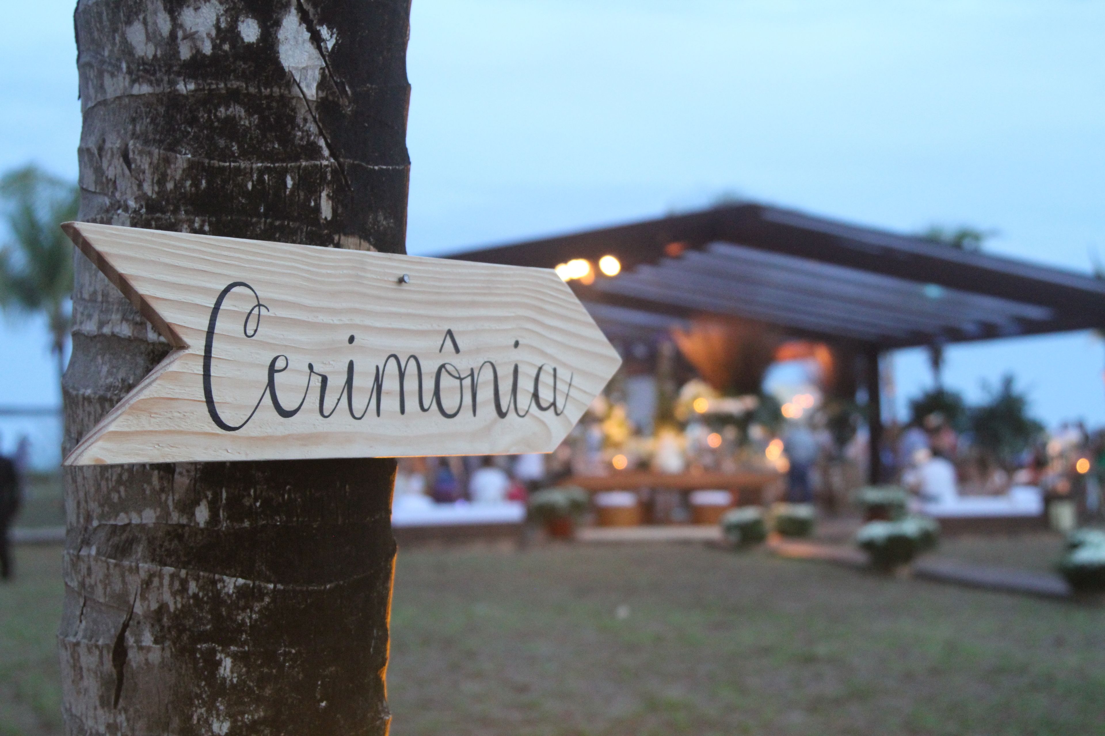 Un letrero de madera con la palabra 'Cerimônia' sujeto a un árbol.