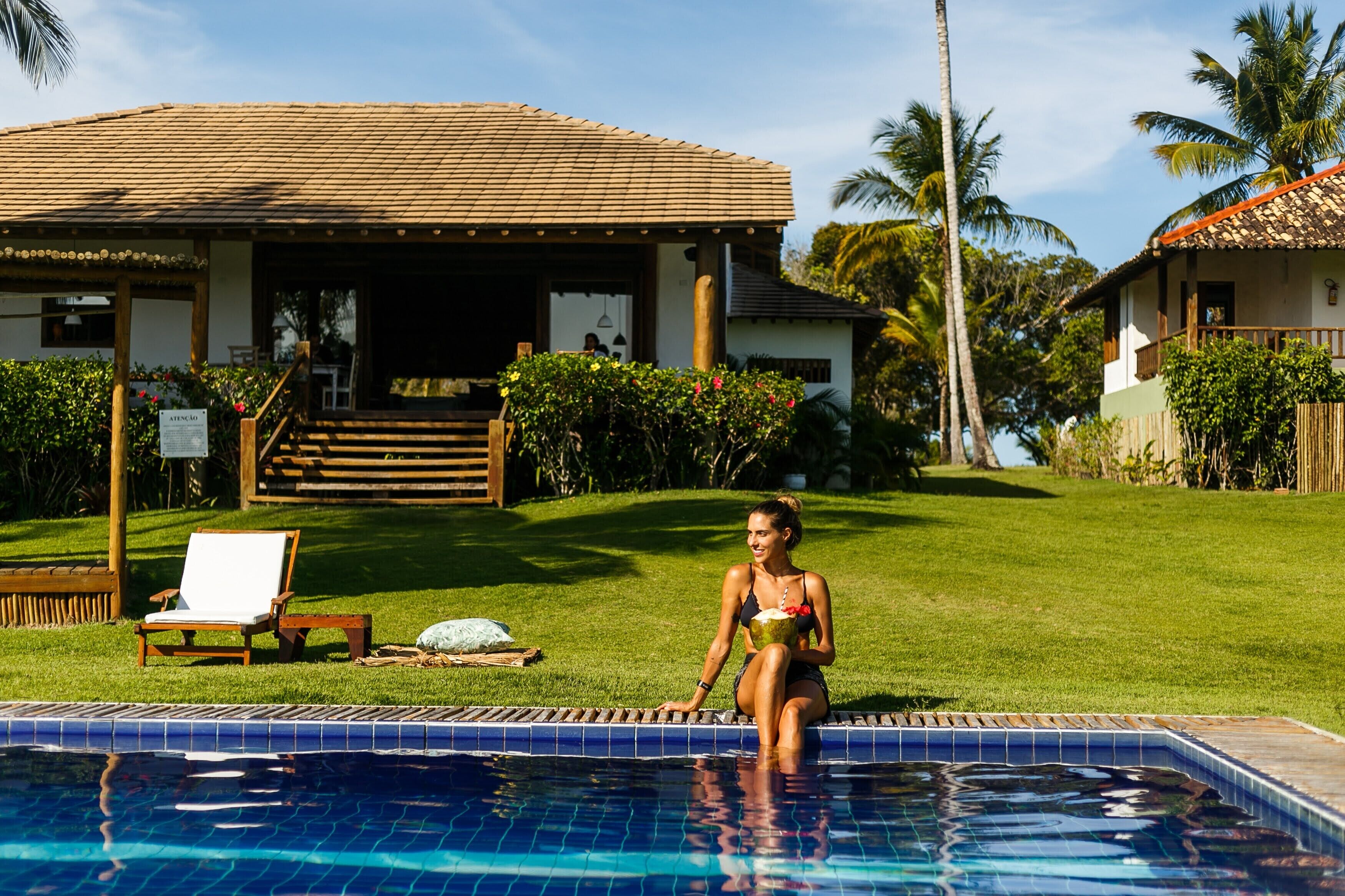 A poolside area with a clear view of a house with a tiled roof and a covered porch.