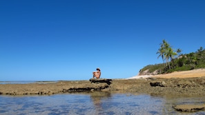 Na praia, areia branca, espreguiçadeiras, toalhas de praia